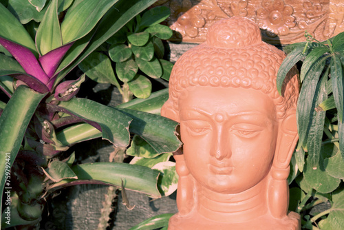 Clay head of Buddha among tropical plants.