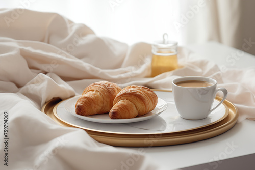 Breakfast tray on a plush white bed with two golden croissants and a cup of coffee. Concept for a luxury lifestyle or a relaxing weekend.