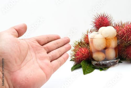 A man's hand holds a glass containing rambutan fruit syrup or (Nephelium lappaceum L) photo