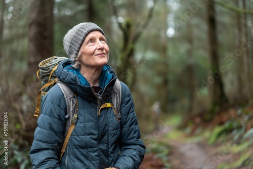 Elderly woman with a backpack looks up in wonder during a forest hike