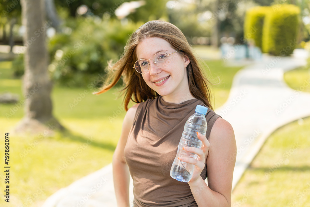 French girl with glasses holding a bottle of water at outdoors smiling a lot French girl with glasses holding a bottle of water at outdoors smiling a lot