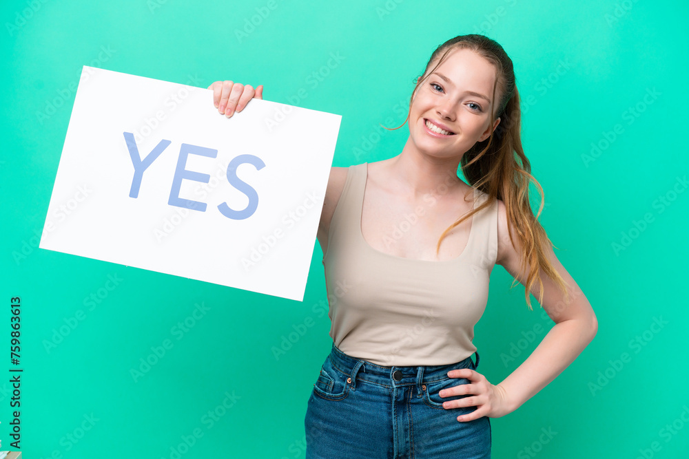 Young caucasian woman isolated on green background holding a placard with text YES with happy expression Young caucasian woman isolated on green background holding a placard with text YES with happy expression