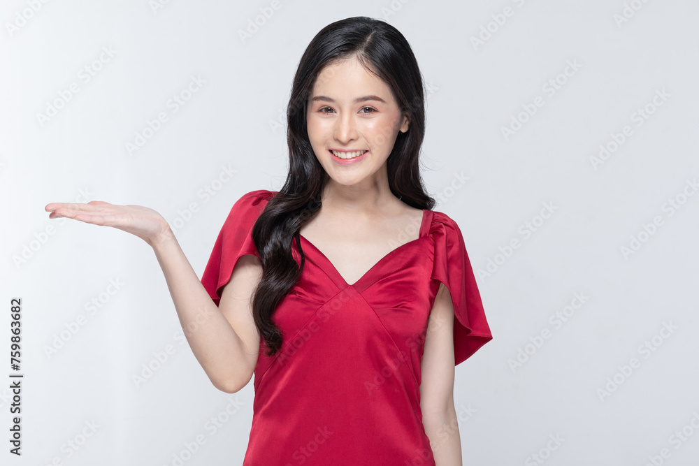 Welcoming young woman presenting with hand in a striking red dress on a white background Welcoming young woman presenting with hand in a striking red dress on a white background