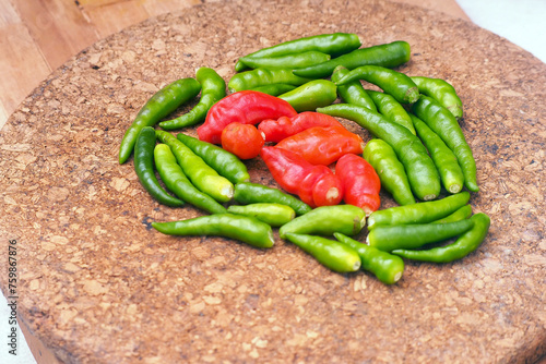 Raw Green chili ( cabe rawit) and red chilli (cabe setan) in a wooden board. (ID: 759867876)