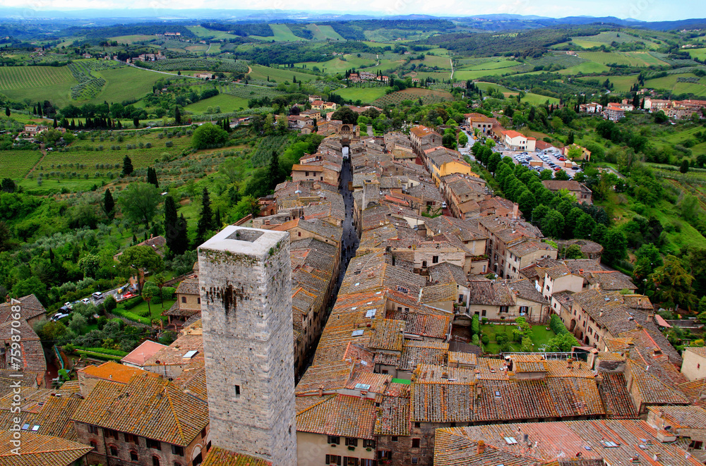 Top view of the historic part of the city with the medieval tower and green valley in the background in San Gimignano, near Siena, in Tuscany region of Italy