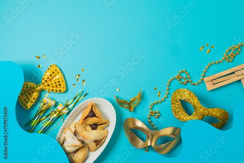 Jewish holiday Purim creative concept  with carnival mask and hamantaschen cookies on blue background. Top view, flat lay  composition