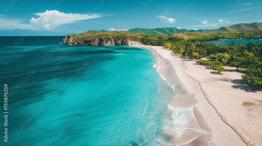 Aerial view of a pristine tropical beach with powdery white sands and crystal clear blue waters, flanked by lush greenery.