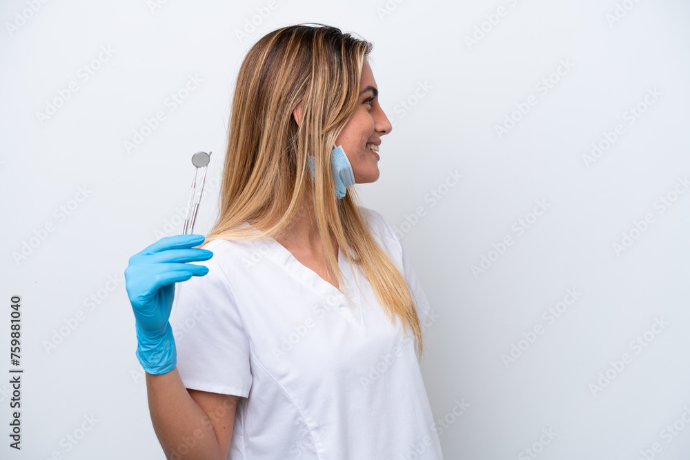 Dentist woman holding tools isolated on white background laughing in lateral position Dentist woman holding tools isolated on white background laughing in lateral position