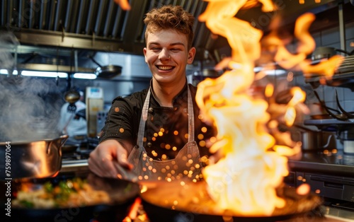 Young European chef grinning as he flames a dish, the kitchen alive with culinary excitement