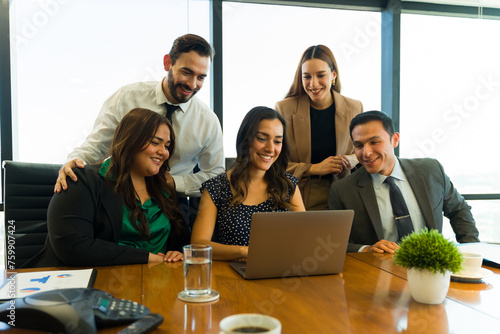 Happy and diverse business team working together and looking at a laptop computer