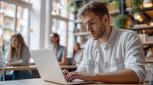 Man working on laptop in cafe, blurr people in background © twentyone