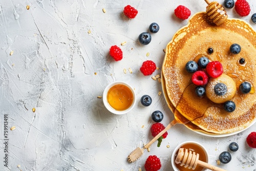 Pancakes topped with fresh blueberries, raspberries, and drizzled with honey, served on a white plate.