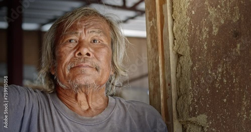 A smiling Asian man who is a homeless ragpicker or has a career collecting garbage and selling it, live in a abandoned house at a slum village. photo