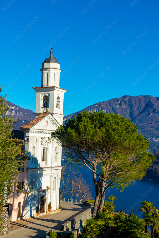 Church of Saints Fedele and Simone and Lake Lugano with Mountain in a Sunny Day in Vico Morcote, Ticino in Switzerland.