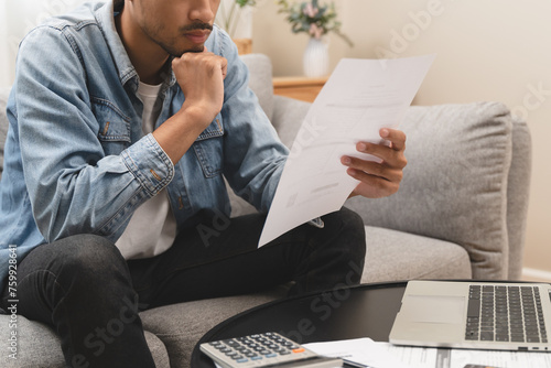 Household financial economic concept, Stressed Young Asian adults are looking at credit card bills issued documents, and apartment loan mortgages and worrying about having no money to pay.