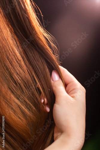 The womans thumb can be seen holding her layered hair in a closeup gesture. She may have artificial hair integrations for a fashion event