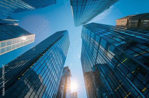 A stock photo of modern skyscrapers with a blue sky and sun shining through the glass windows, representing corporate architecture in an urban setting