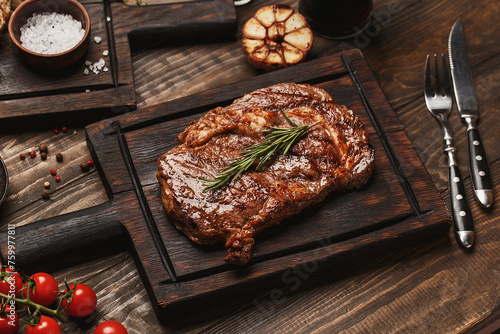 Konstfotografi Grilled ribeye beef steak served on wooden board with rosemary, grilled garlic,
