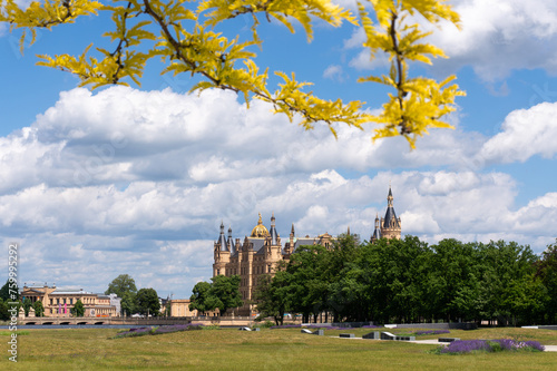 View over floating meadow in the direction of Schwerin Castle and the State Chancellery. branch with yellow leaves. Sunny day with beautiful clouds.