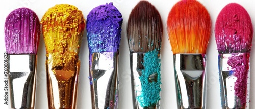  A row of vibrant paintbrushes arranged on a white backdrop against a pure white wall