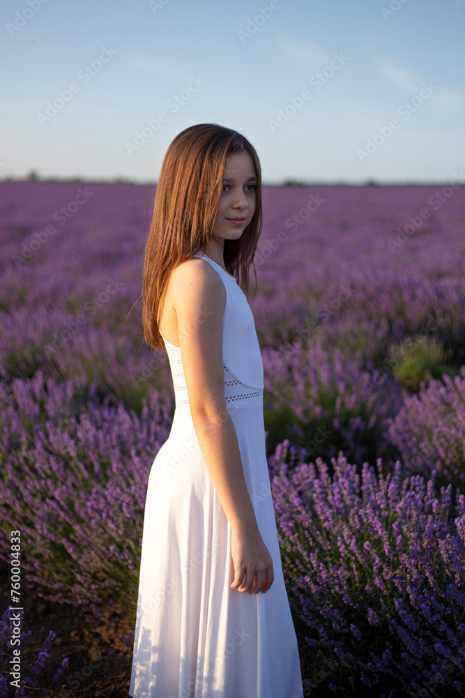 Side view of a young girl poses in a field of lavender flowers at sunset. Side view of a young girl poses in a field of lavender flowers at sunset.