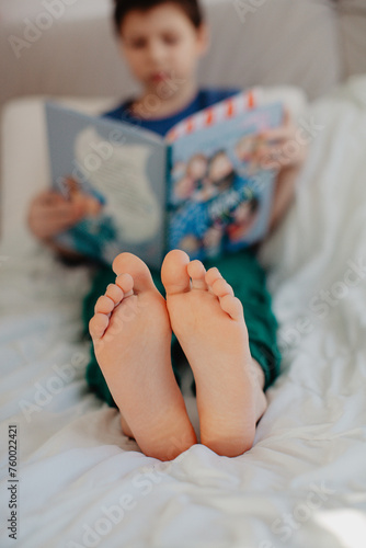 Boy is reading in the bedroom on the bed
