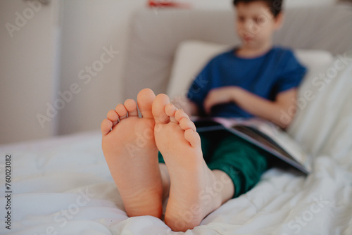 Boy is reading in the bedroom on the bed