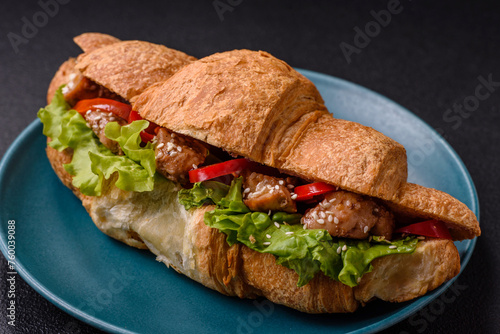 Delicious fresh crispy croissant with chicken or beef meat, lettuce, tomatoes, spices and sauce