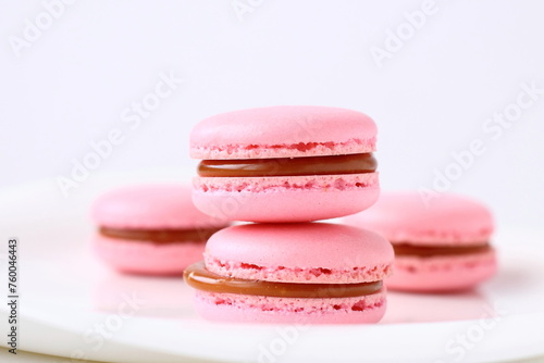 Pink French macaroons dessert on a plate white background. Sweet handmade almond macarons with salted caramel filling  for breakfast or Birthday, coffee break. Close up © Foodie Studio
