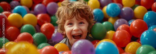 Caucasian boy in a pile of colorful plastic balls.