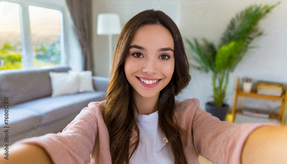 Selfie picture of a happy young pretty millennial woman smiling at the camera in the living room in a modern home Selfie picture of a happy young pretty millennial woman smiling at the camera in the living room in a modern home