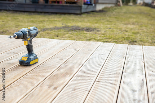 Power drill on newly constructed wooden deck, home improvement and DIY concept with space for text