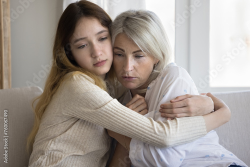 Loving empathetic pre-teen daughter cuddling her mature frustrated mother, caring child is near in hard life period, crisis, divorce or break up. Warm family relationship, love and emotional support photo