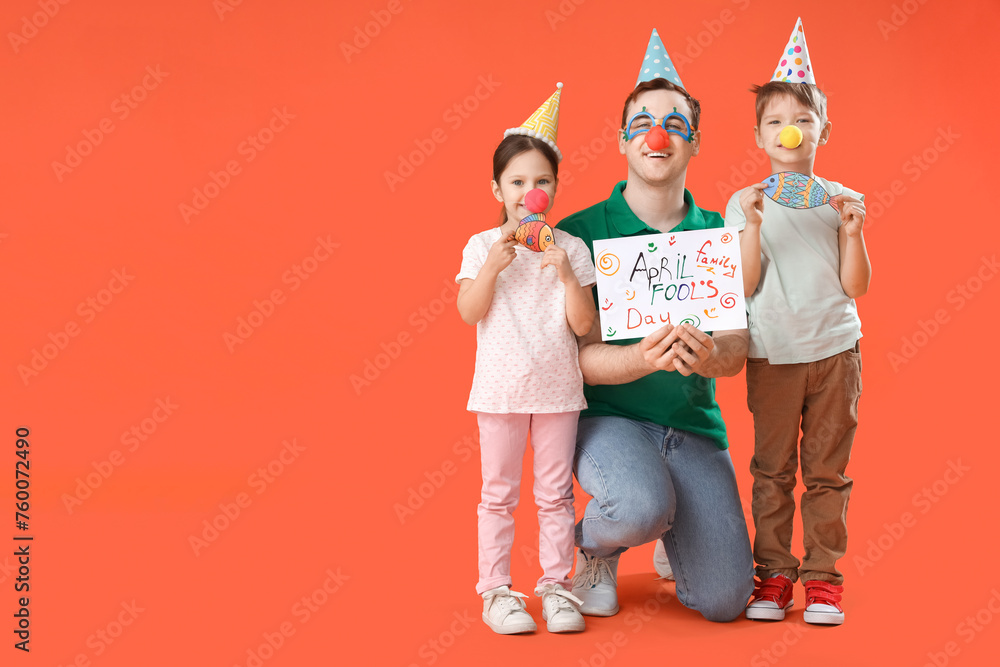 Φωτογραφία Father and his little children with funny disguises and paper fishes on orange background