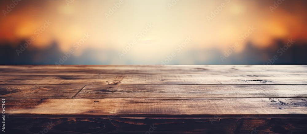 A wooden table sits empty against the backdrop of a stunning sunset. The vibrant colors of the sky merge into the horizon, creating a picturesque evening landscape - obrazy, fototapety, plakaty 