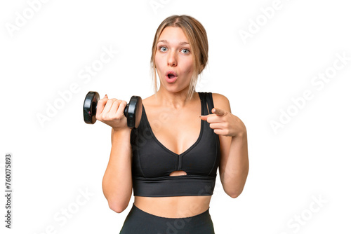 Blonde sport woman making weightlifting over isolated chroma key background surprised and pointing front