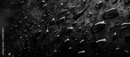 Droplets on black surface. Water beads scattered across a dark, sleek texture