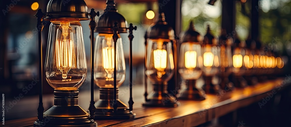 A row of lanterns illuminating a wooden table at an outdoor event. The buildings facade reflected in the glass bottles and barware on display - obrazy, fototapety, plakaty 