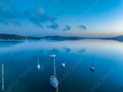 Aerial sunrise waterscape with boats, reflections and low cloud