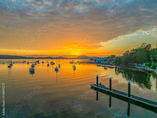 Aerial sunrise over the water with boats and clouds © Merrillie
