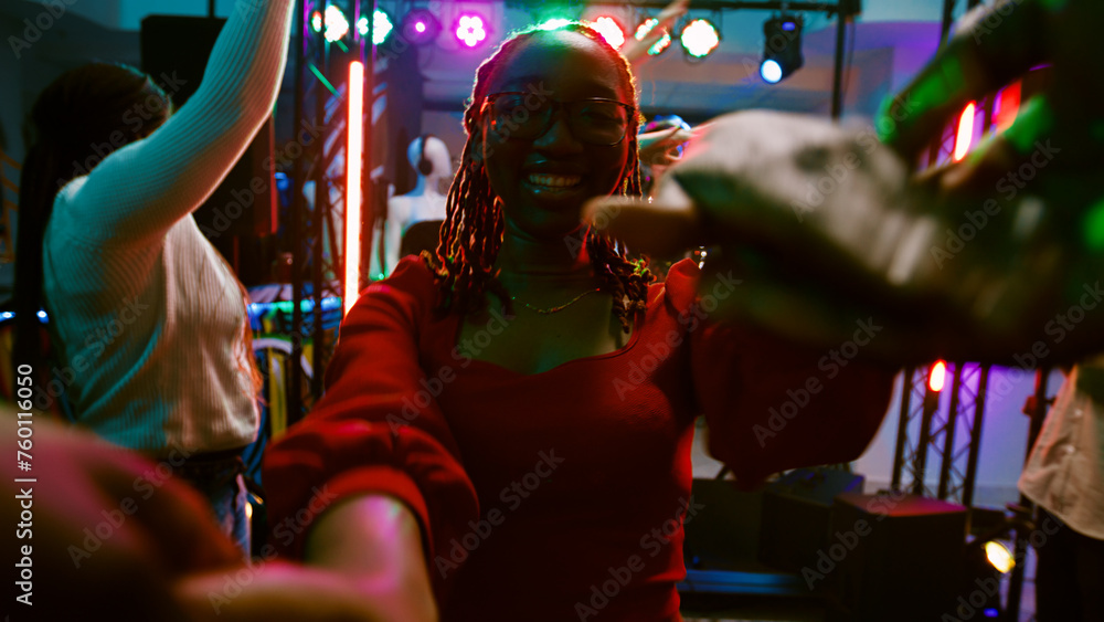 POV of girl dancing with someone at club, enjoying disco party on discotheque dance floor. Group of friends having fun at nightclub listening to electronic music, entertainment. Handheld shot.