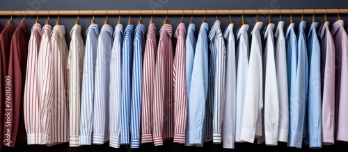 A row of shirts in electric blue and magenta colors, hanging on metal clothes hangers in a closet. The room is filled with fashion design for an event