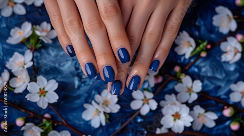 Female hands with blue nail design. Woman hands with trendy polish manicure on background with spring flowers