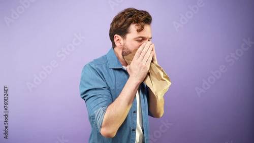 Man in a studio having a panic attack and using a paper bag to breathe and calm down