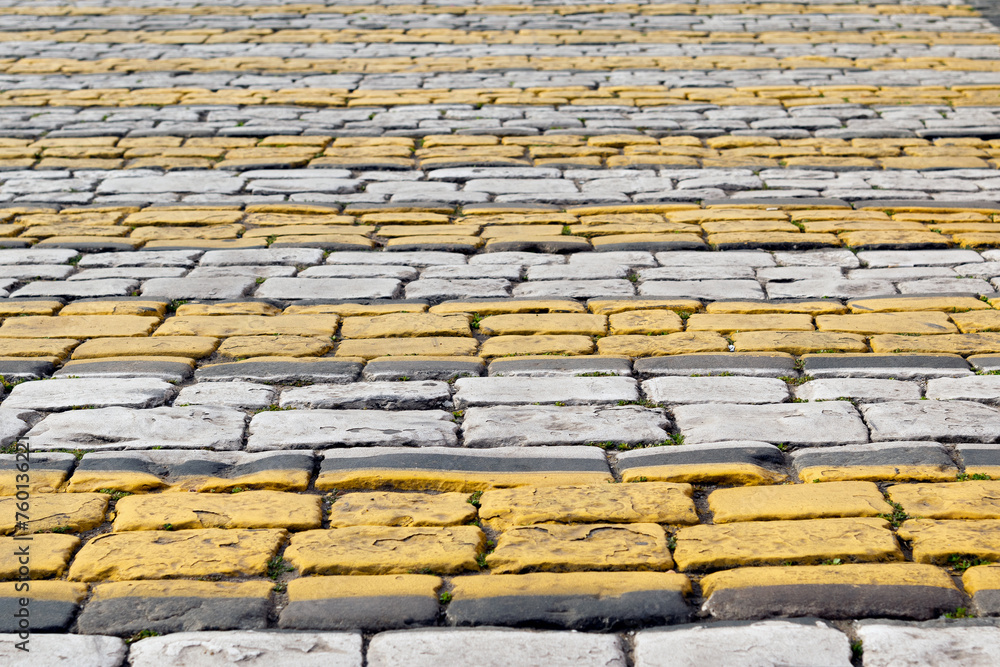 Cobblestone pavement painted with white and yellow stripes, pedestrian crossing, brick road - background is blurred, bokeh, selective focuse