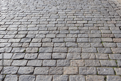 City square street lined with square gray bricks, cobblestones, city pavement all over the square to the horizon - close-up, blurred background
