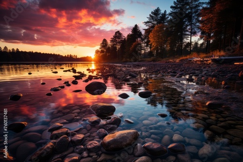 Sunset sky reflected in the lake, rocks in foreground, trees in background
