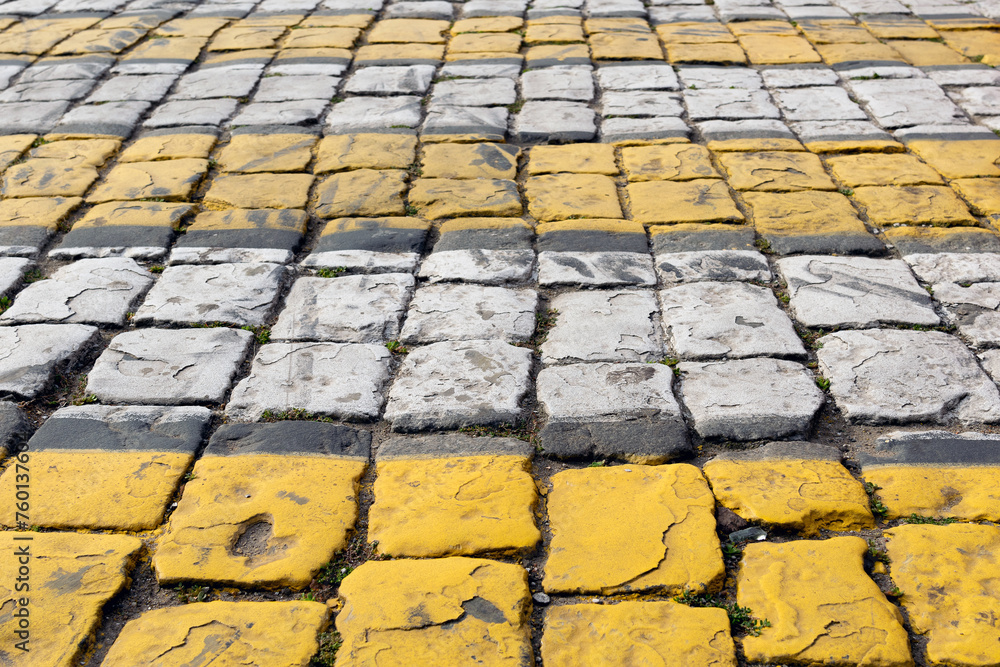 Cobblestone pavement painted with white and yellow stripes, pedestrian crossing, brick road - background is blurred, bokeh, selective focuse