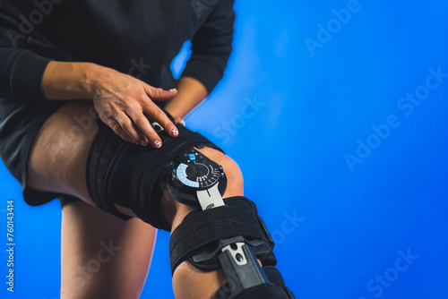 closeup shot of a woman with leg bandage compression brace on a blue background, injury and recovery concept. High quality photo
