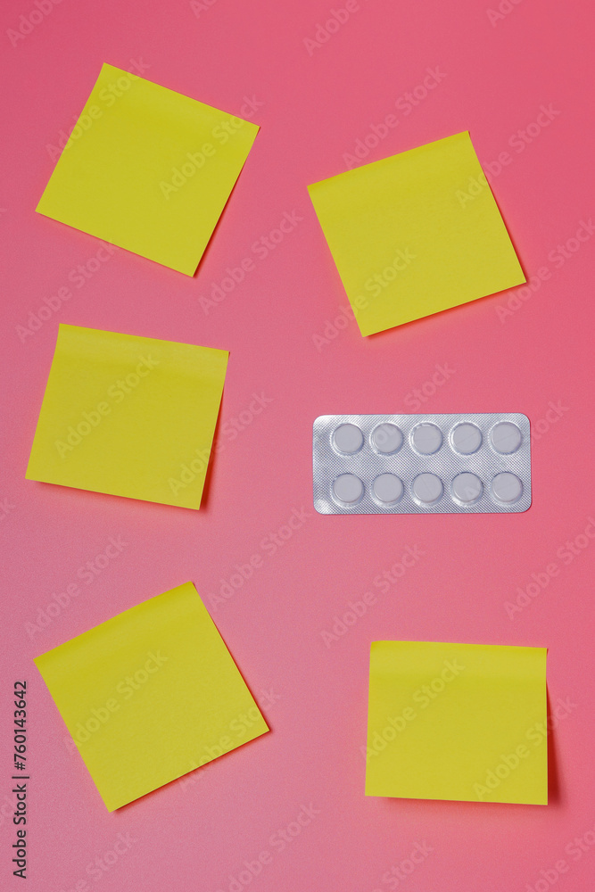A pack of pills and a few yellow notes on a pink background - healthcare, scheduled medications, therapy, contraception, timetable, vertical view